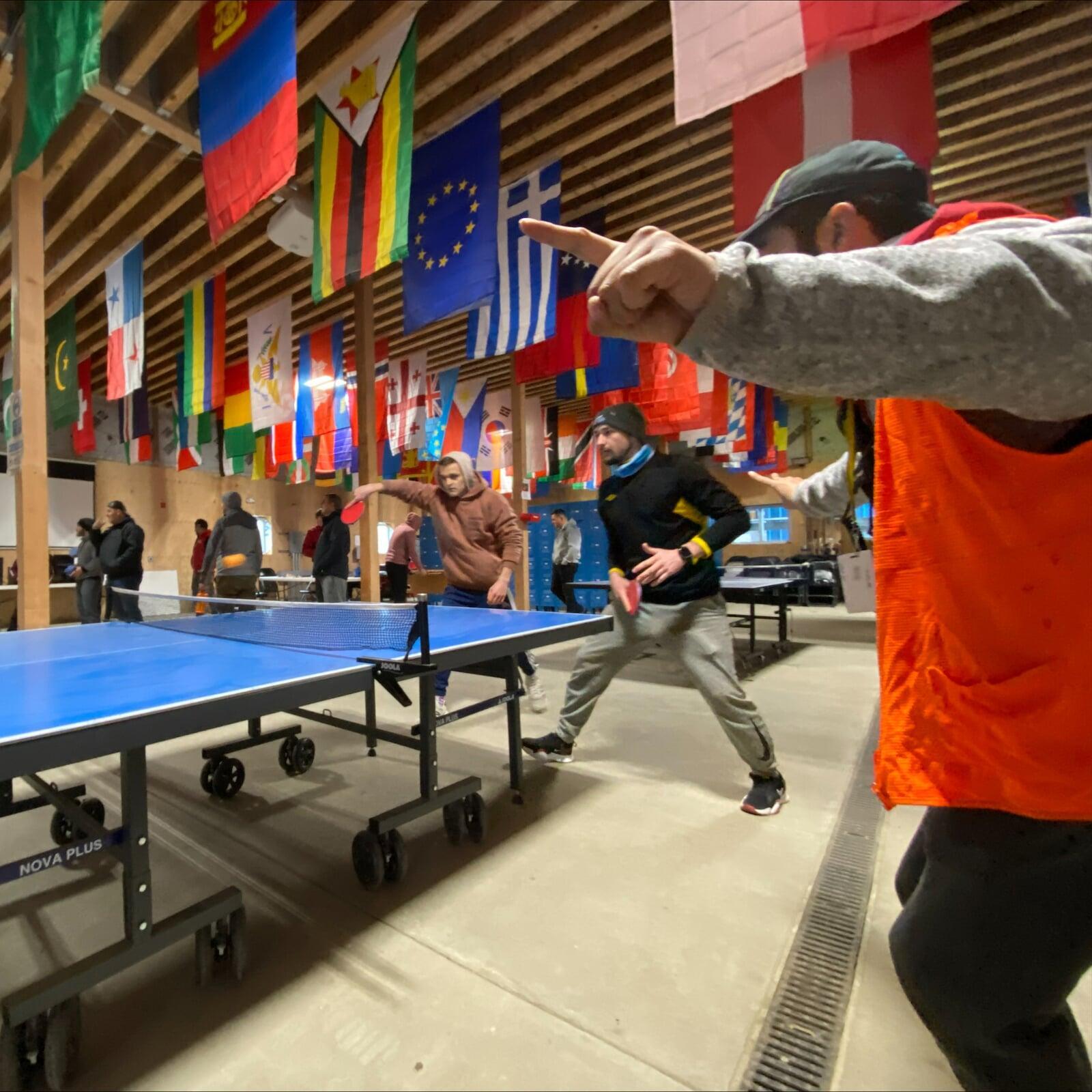 Picture of SBS employees playing ping pong under colorful national flags